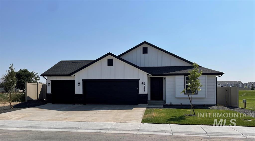 Modern farmhouse with an attached garage, roof with shingles, concrete driveway, and board and batten siding