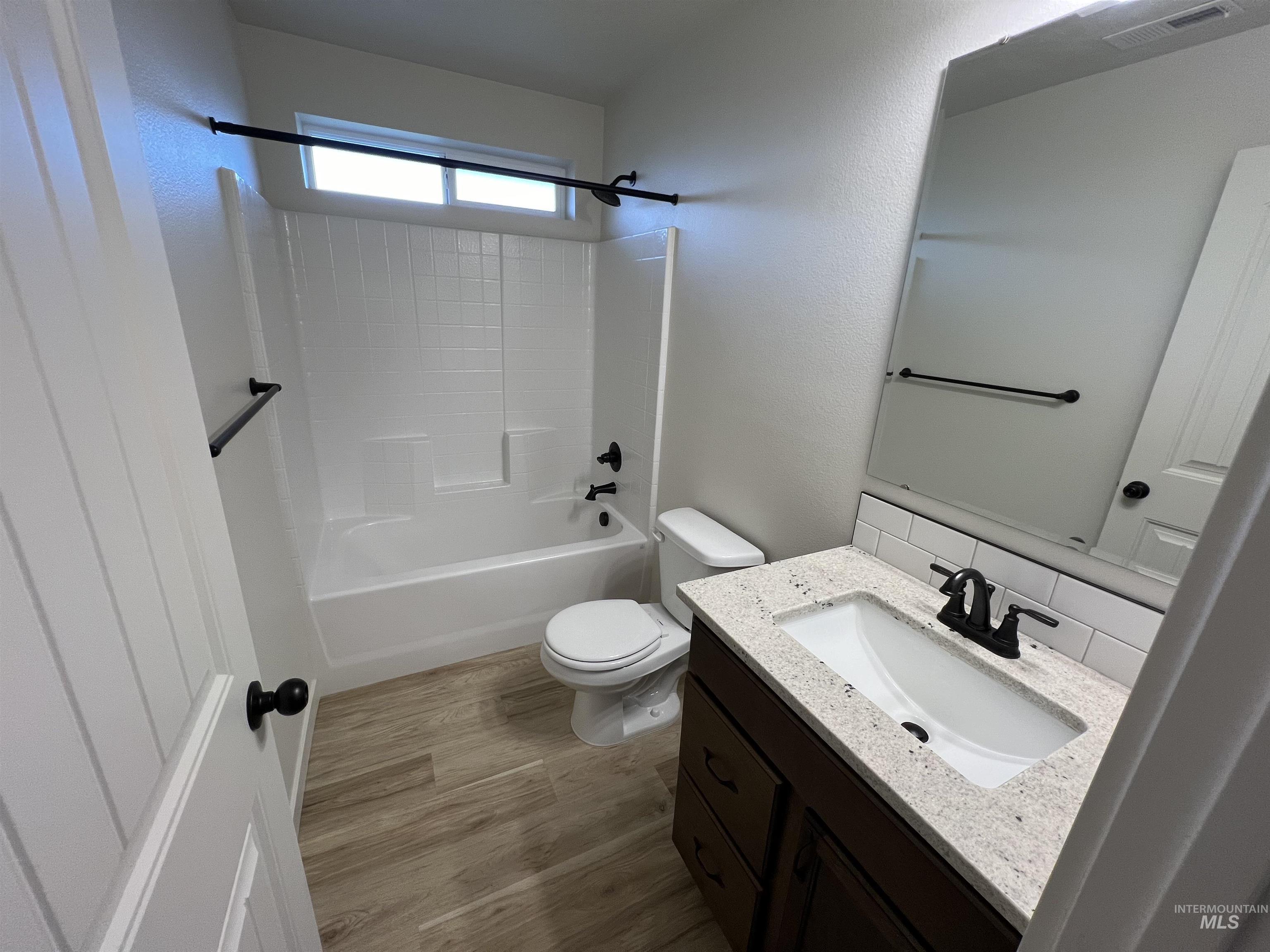 Full bathroom with vanity, light wood finished floors, and shower / tub combination