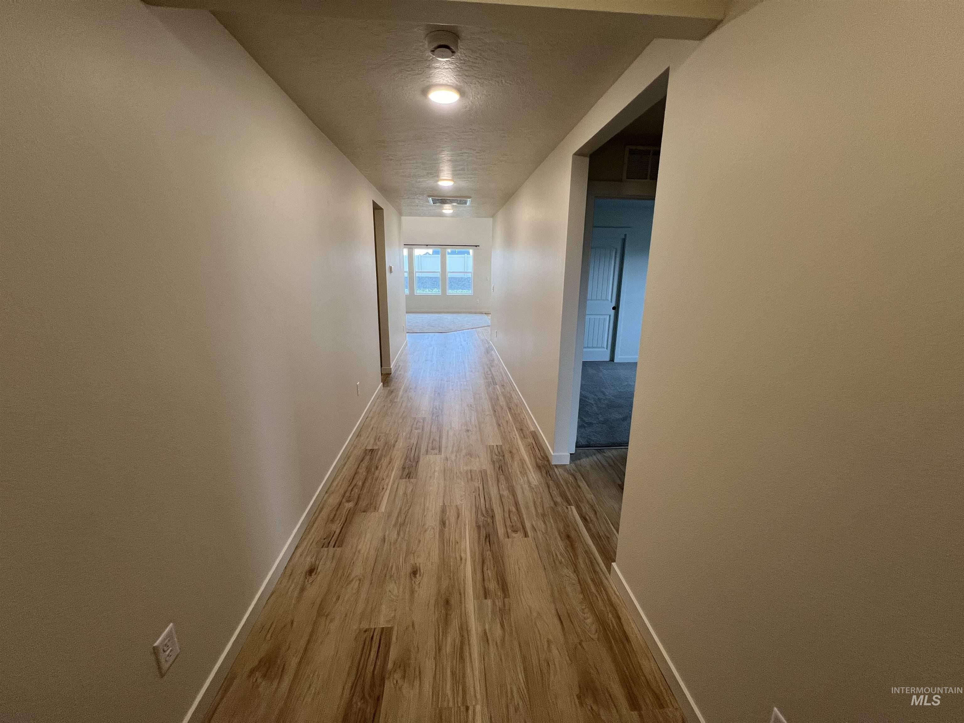 Corridor featuring light wood-style floors and a textured ceiling