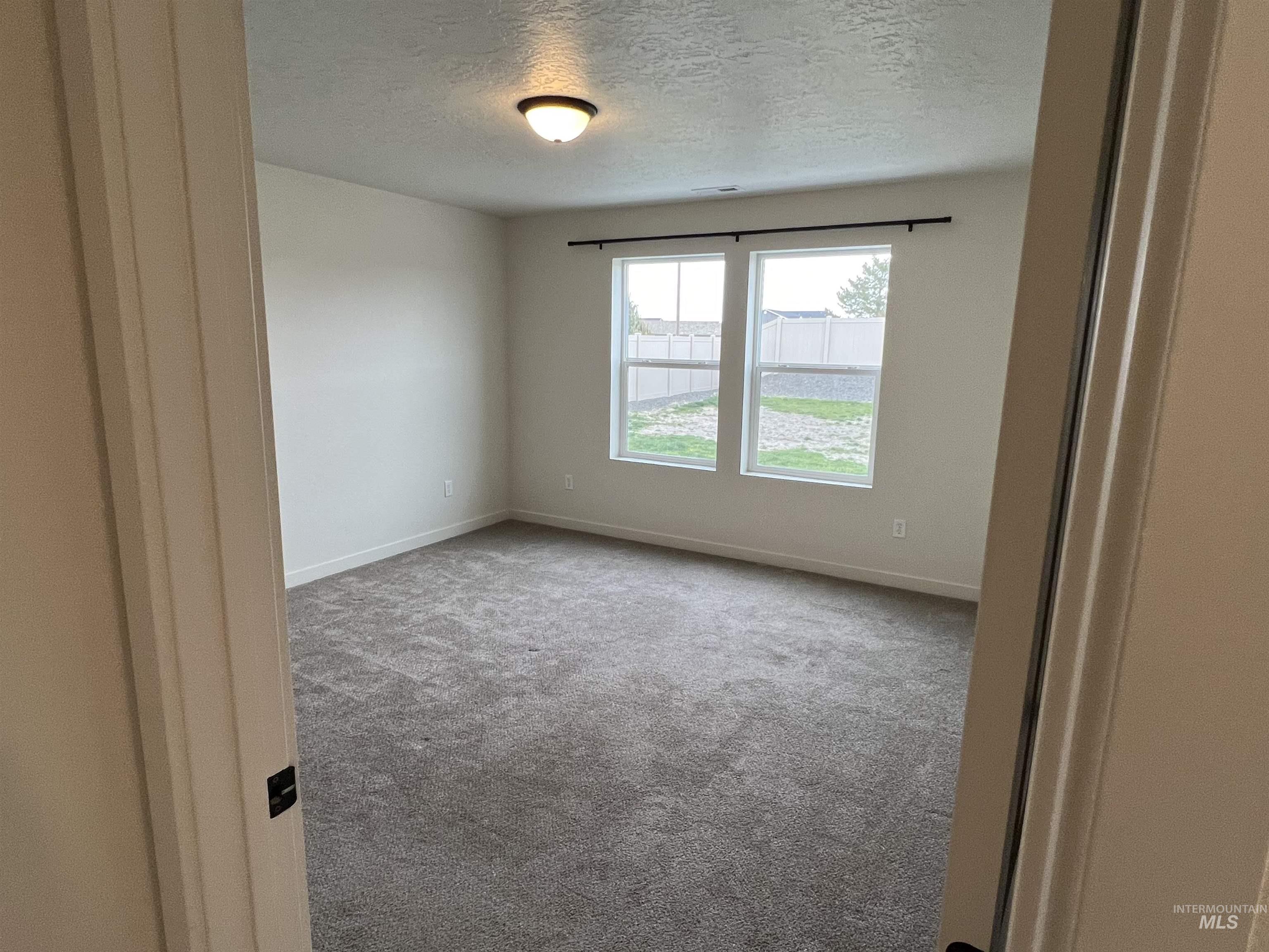Unfurnished room with a textured ceiling and carpet floors