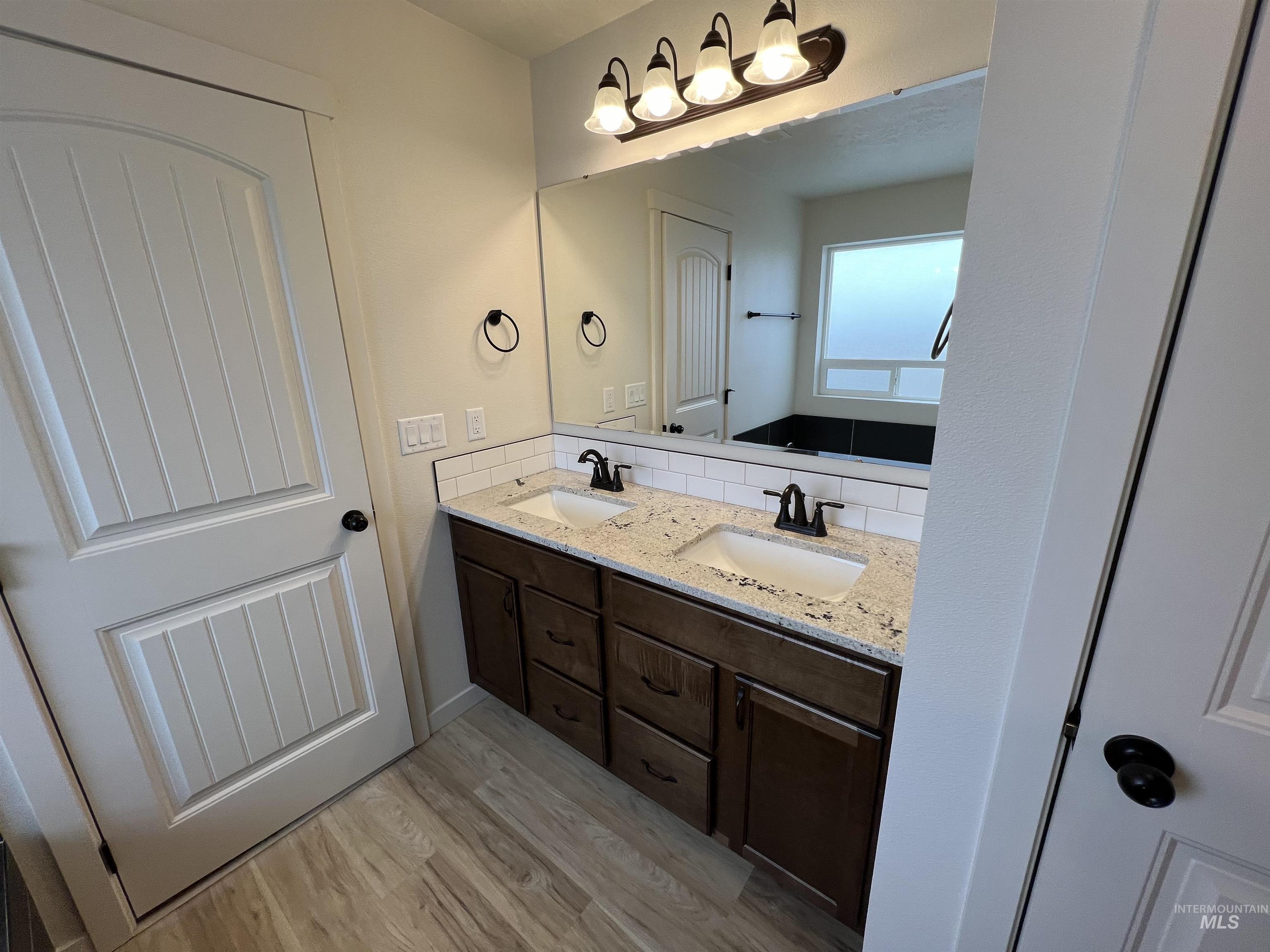 Bathroom featuring double vanity and light wood finished floors