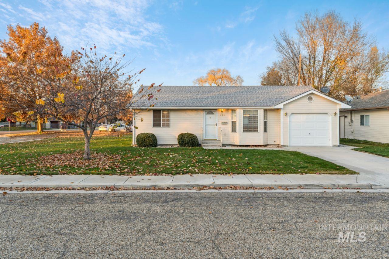 View of front of property featuring concrete driveway, a front lawn, a garage, and a shingled roof
