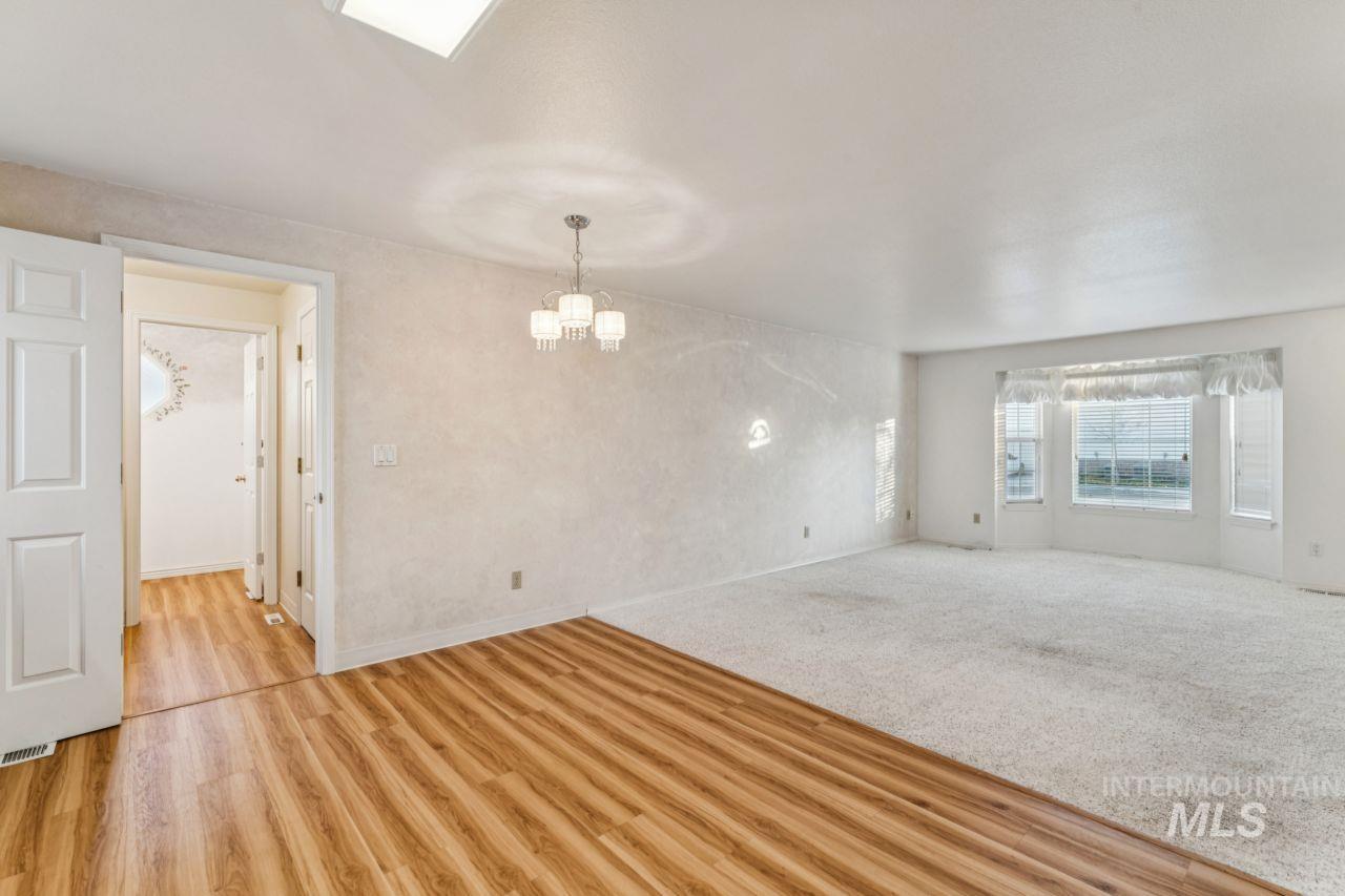 Empty room featuring a chandelier, light carpet, and light wood-style floors