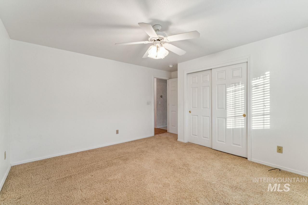 Unfurnished bedroom featuring light carpet, a closet, and a ceiling fan