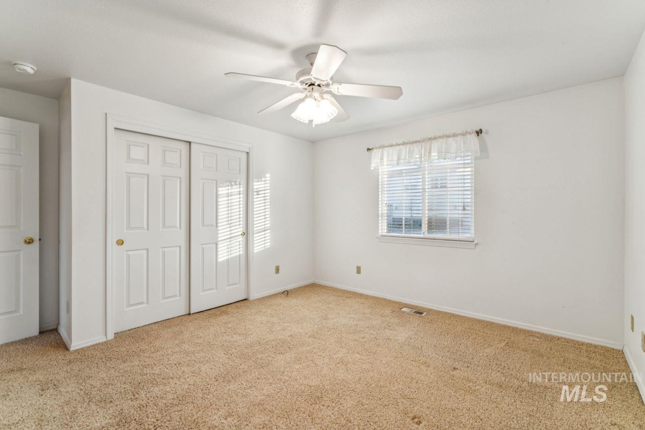Unfurnished bedroom with light carpet, a closet, and a ceiling fan