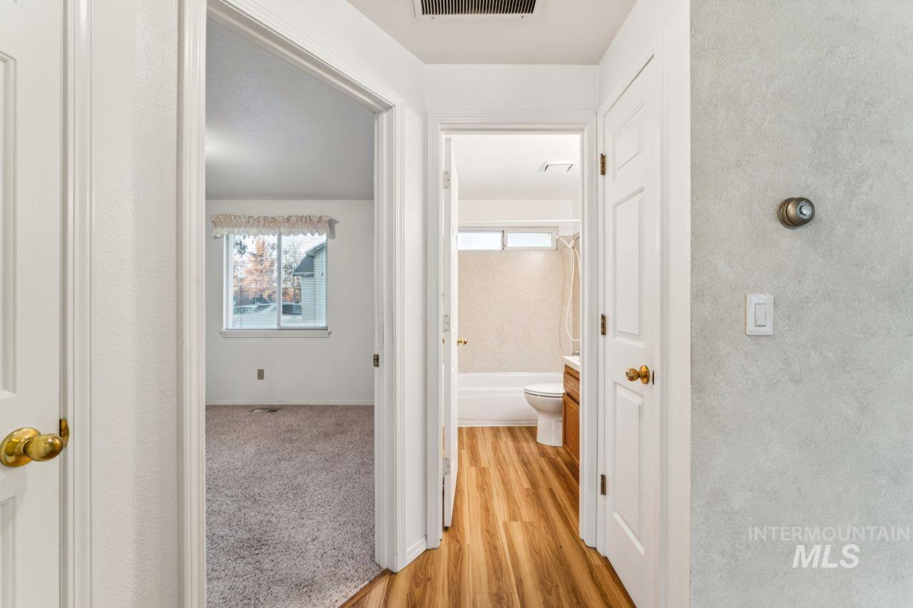 Hallway with healthy amount of natural light, light wood-style floors, and light carpet