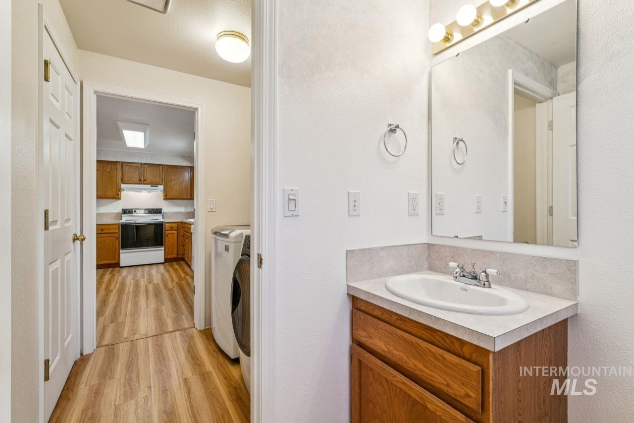 Bathroom with washing machine and clothes dryer, vanity, light wood-type flooring, and a textured wall