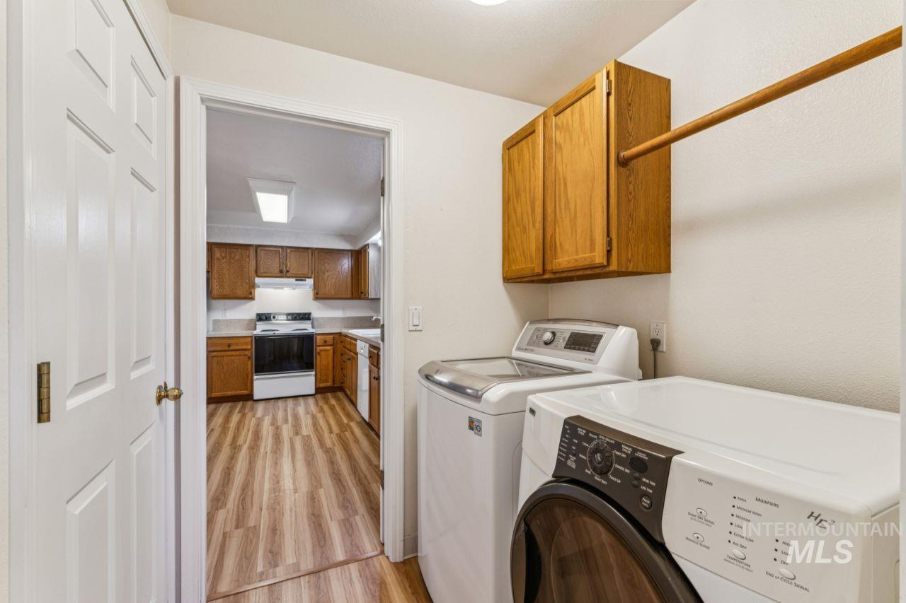 Laundry room with washer and dryer, cabinet space, and light wood finished floors
