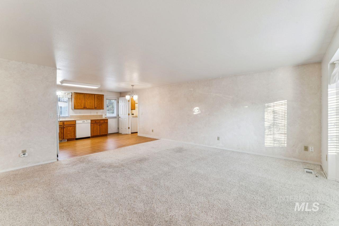 Unfurnished living room with light colored carpet and a chandelier