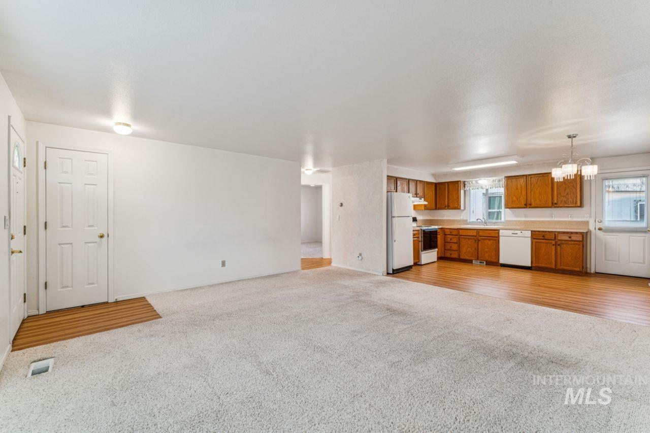 Unfurnished living room featuring light carpet and a chandelier