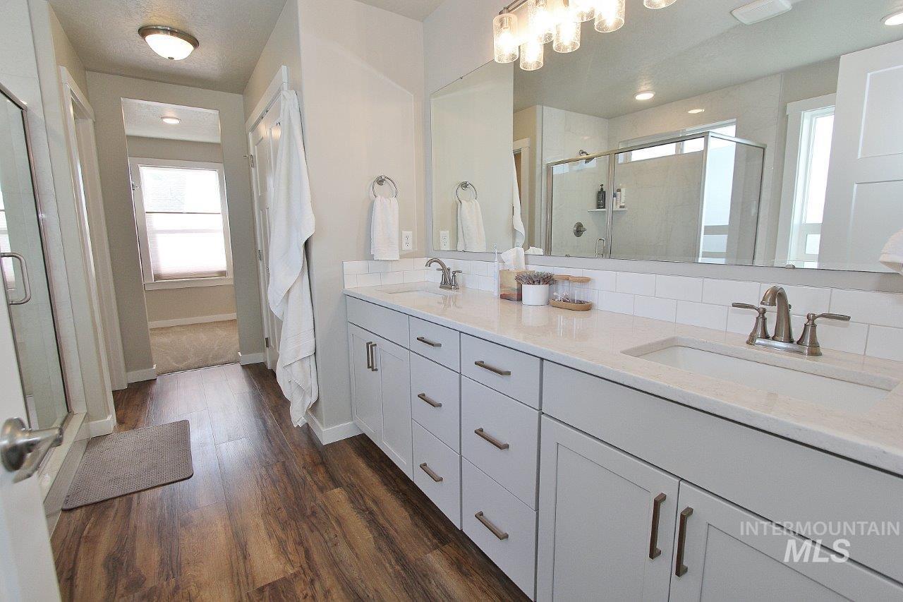 Bathroom with double vanity, a shower stall, and dark wood finished floors