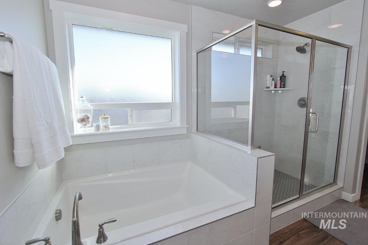 Full bathroom with a shower stall, a garden tub, and wood finished floors