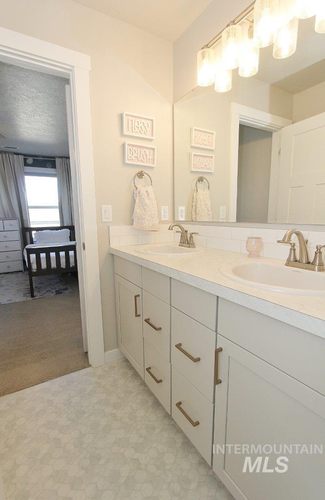 Full bathroom featuring double vanity, light floors, a textured ceiling, light carpet, and ensuite bath