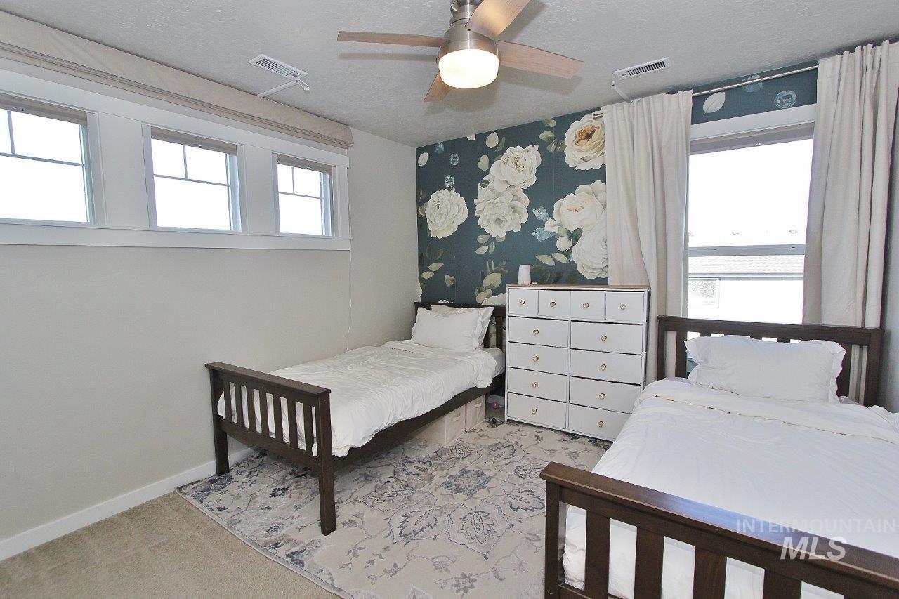 Bedroom with light colored carpet, ceiling fan, and a textured ceiling