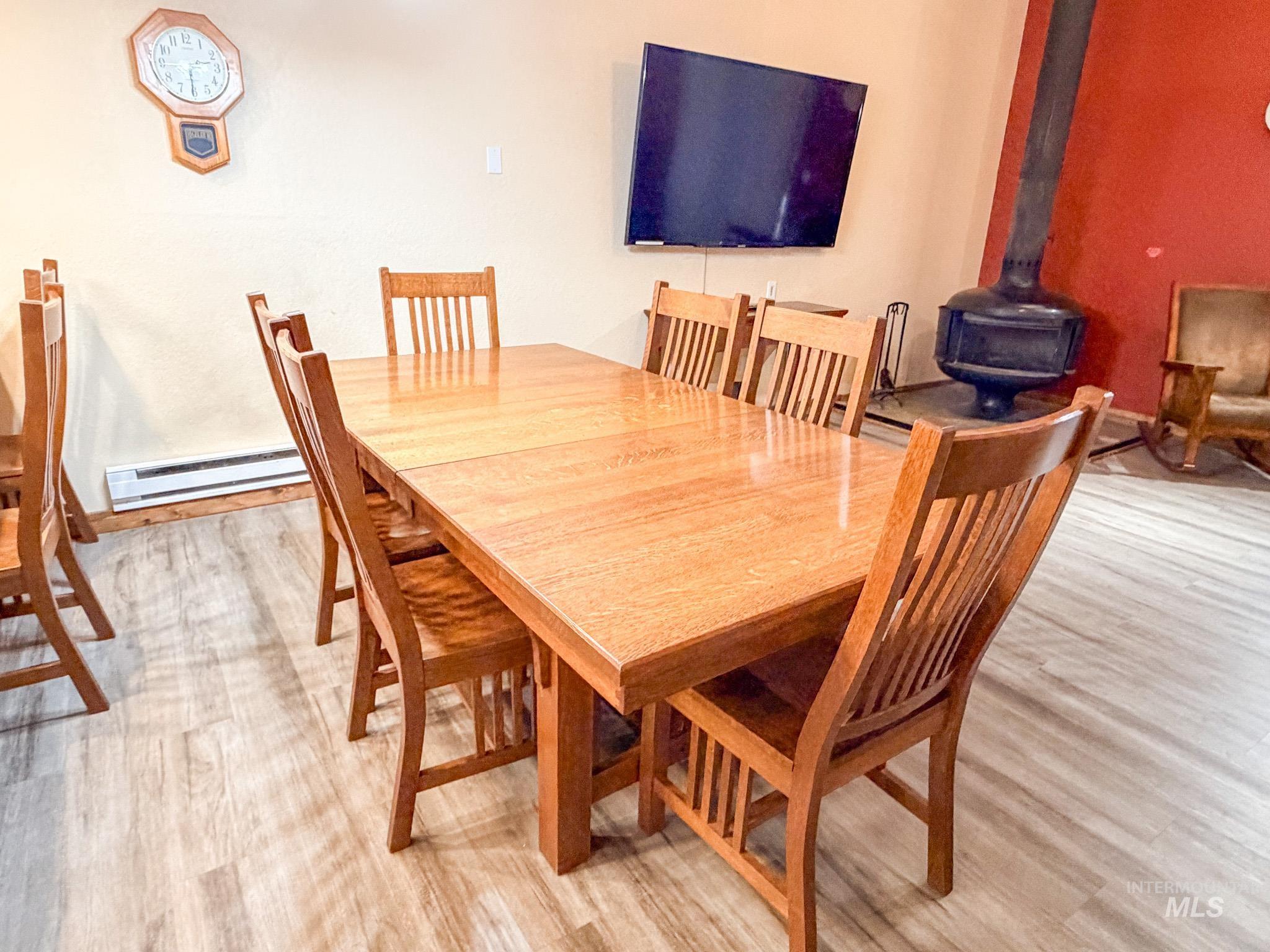 Dining room featuring a wood stove, a baseboard radiator, and light wood-type flooring