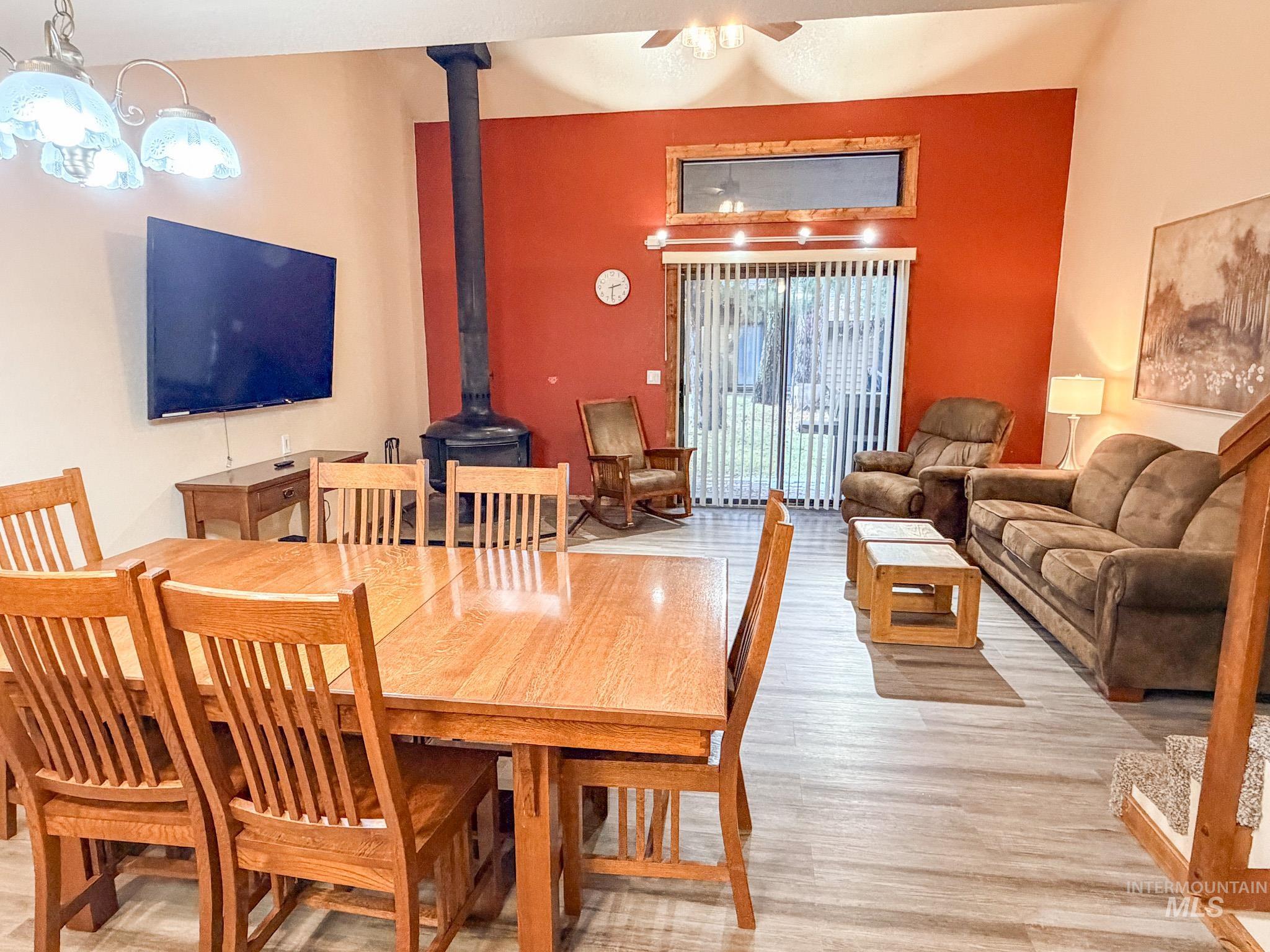 Dining space with a wood stove, light wood-type flooring, and a ceiling fan