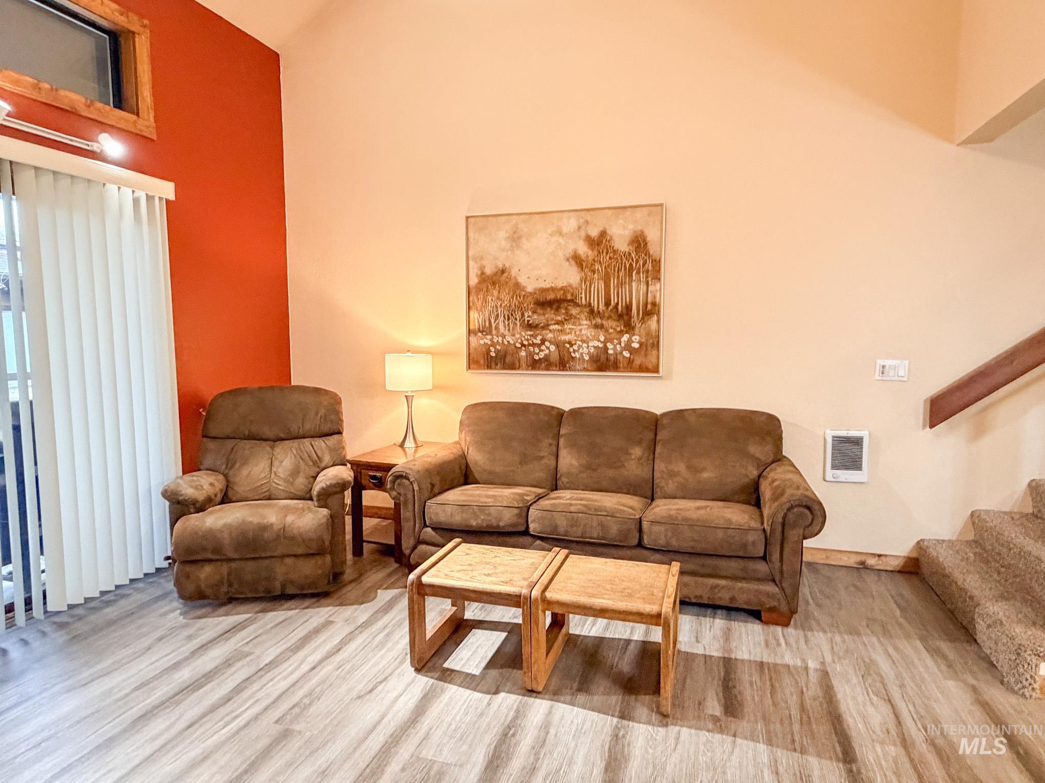 Living area featuring wood finished floors, stairway, vaulted ceiling, and heating unit