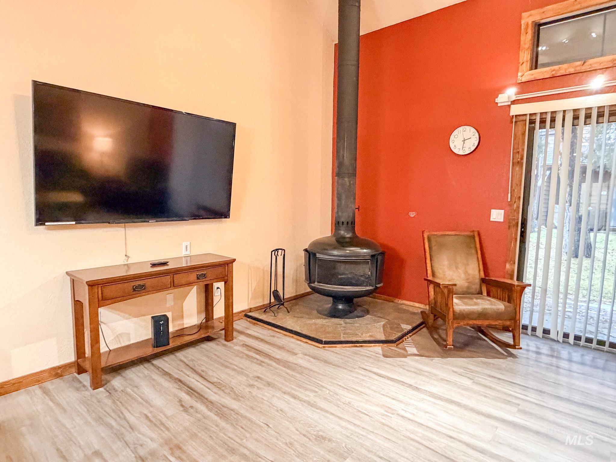 Living area featuring a wood stove, wood finished floors, and a towering ceiling