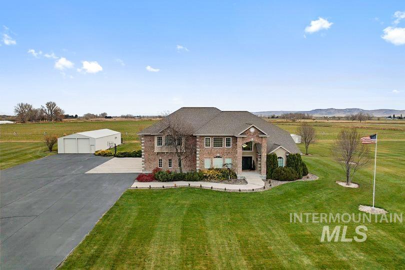 View of front of property featuring brick siding, a front lawn, an outbuilding, and a view of countryside