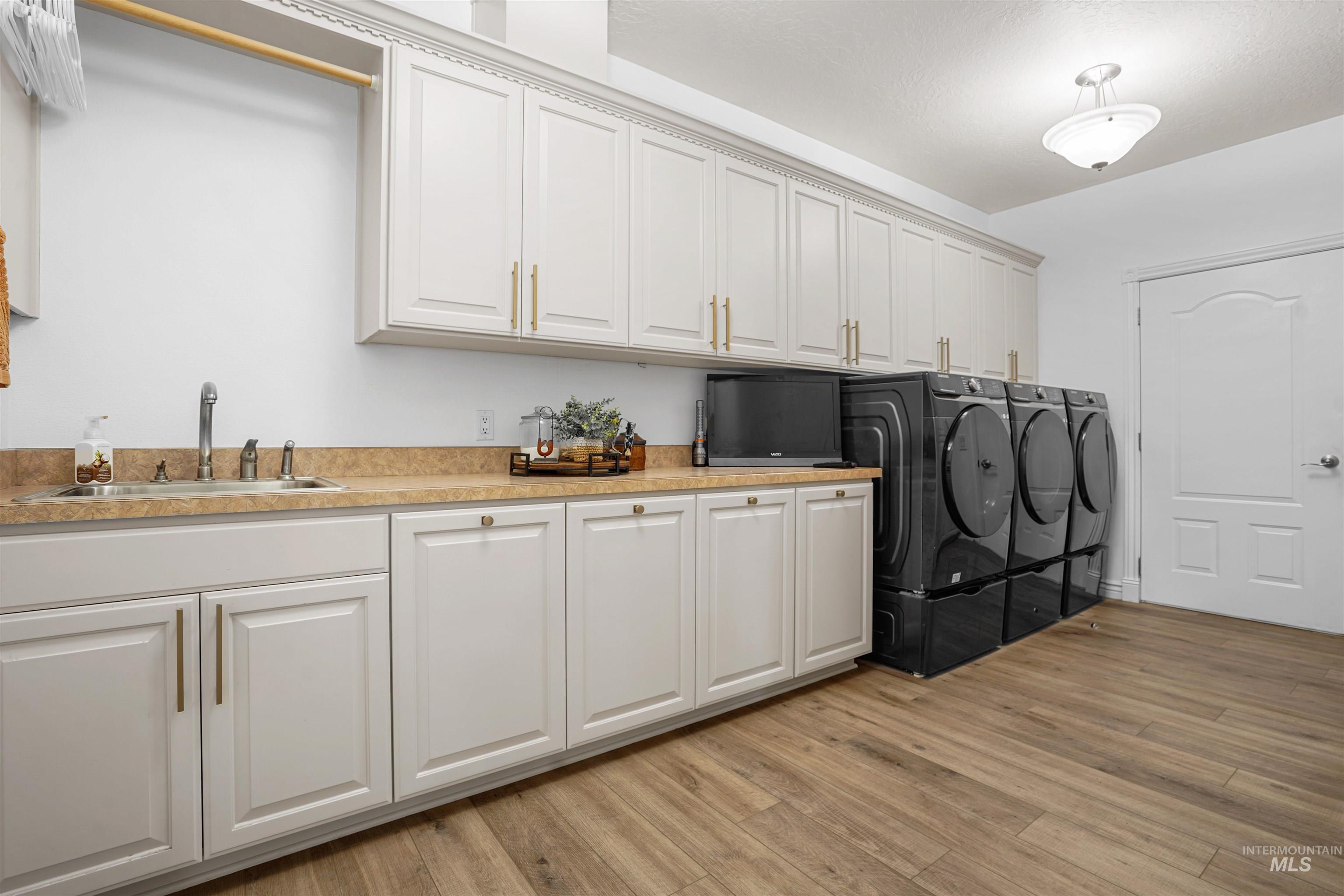 Washroom featuring cabinet space, light wood finished floors, and washing machine and dryer