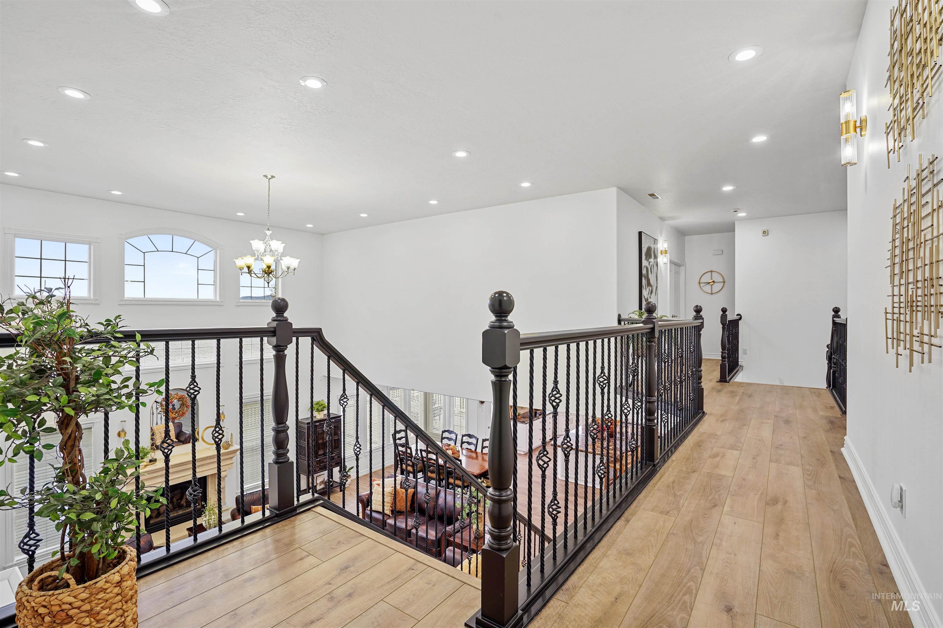 Hallway featuring an upstairs landing, a chandelier, light wood-style flooring, and recessed lighting