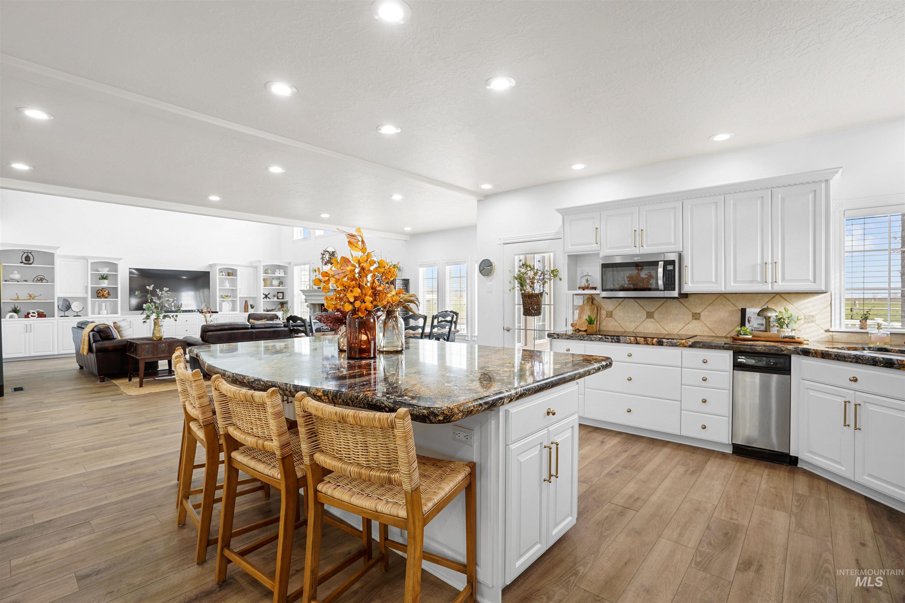 Kitchen featuring a kitchen breakfast bar, white cabinetry, open floor plan, a center island, and light wood-style floors