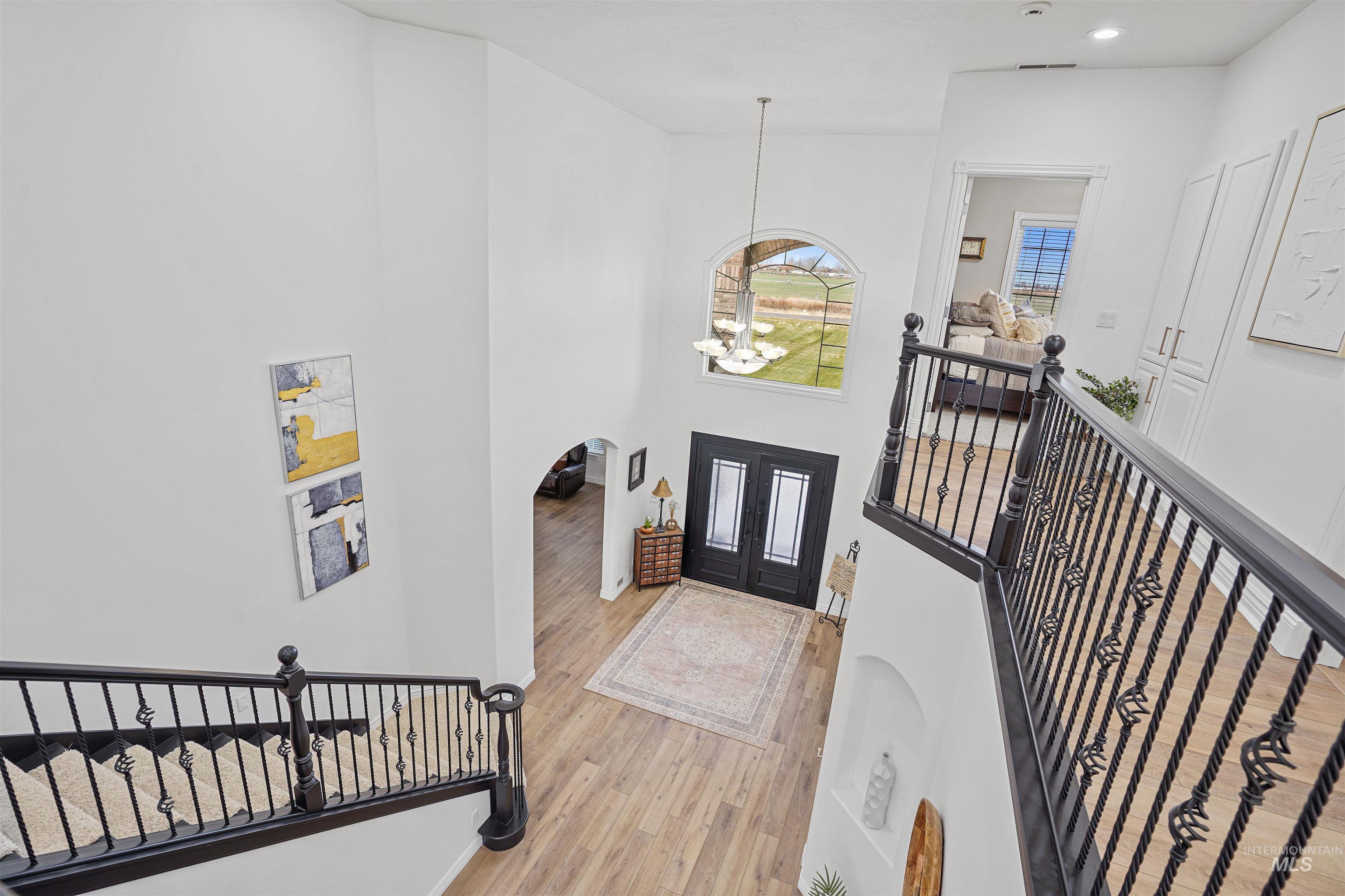Entrance foyer with a chandelier, light wood-style floors, and a towering ceiling