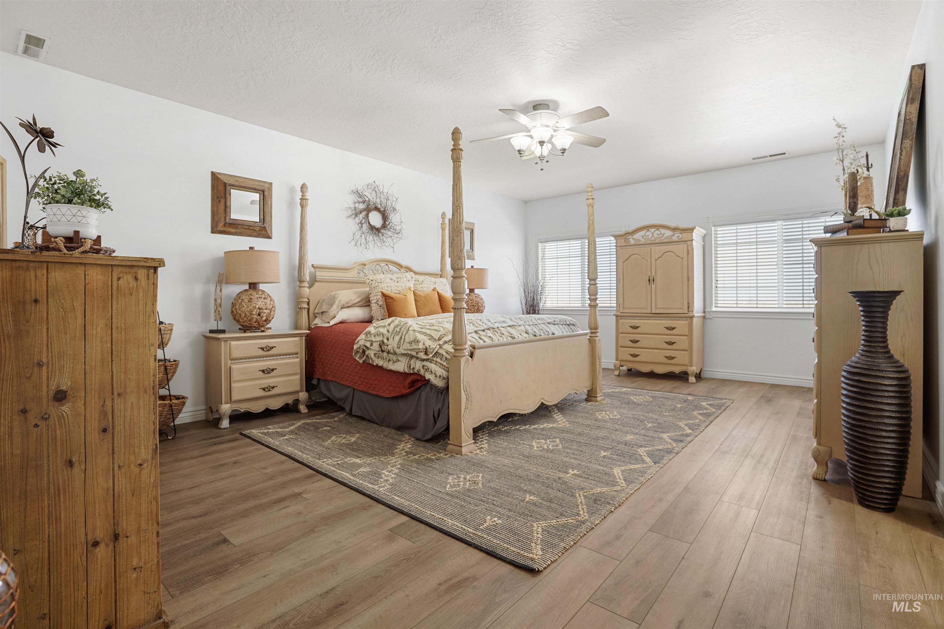 Bedroom with light wood-style floors, a textured ceiling, and ceiling fan