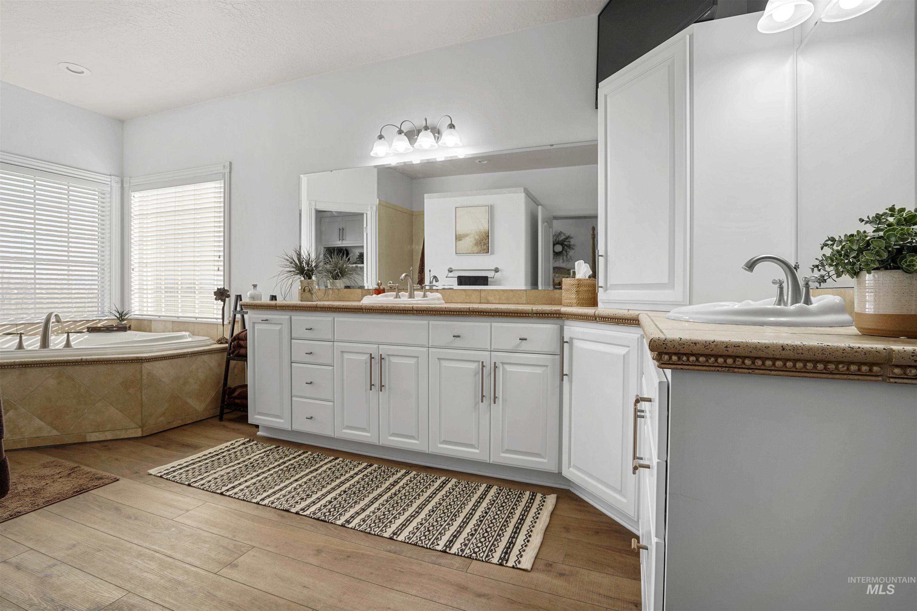 Bathroom featuring vanity, a bath, and light wood-type flooring