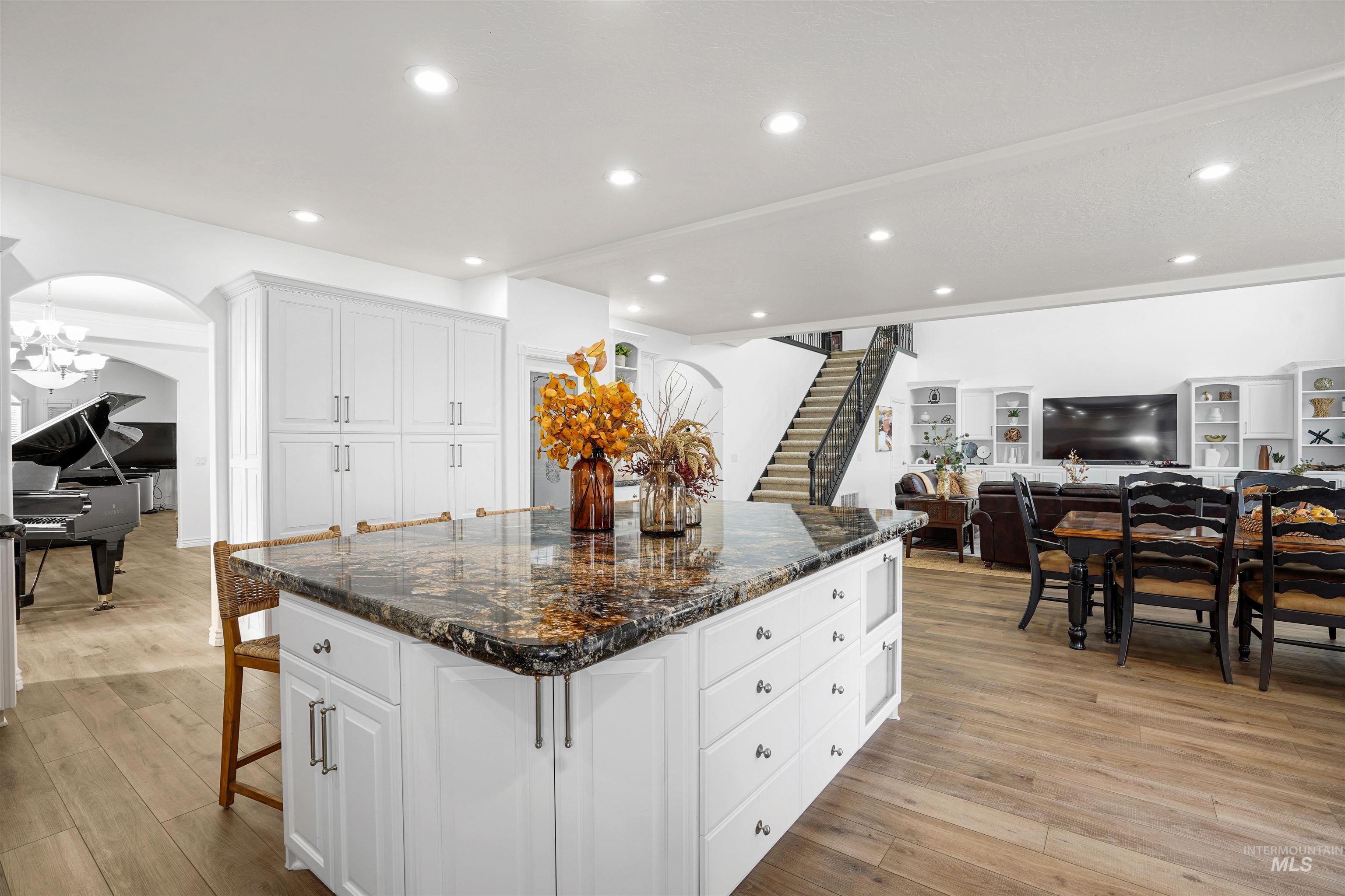 Kitchen featuring dark stone countertops, white cabinets, open floor plan, a center island, and a breakfast bar area