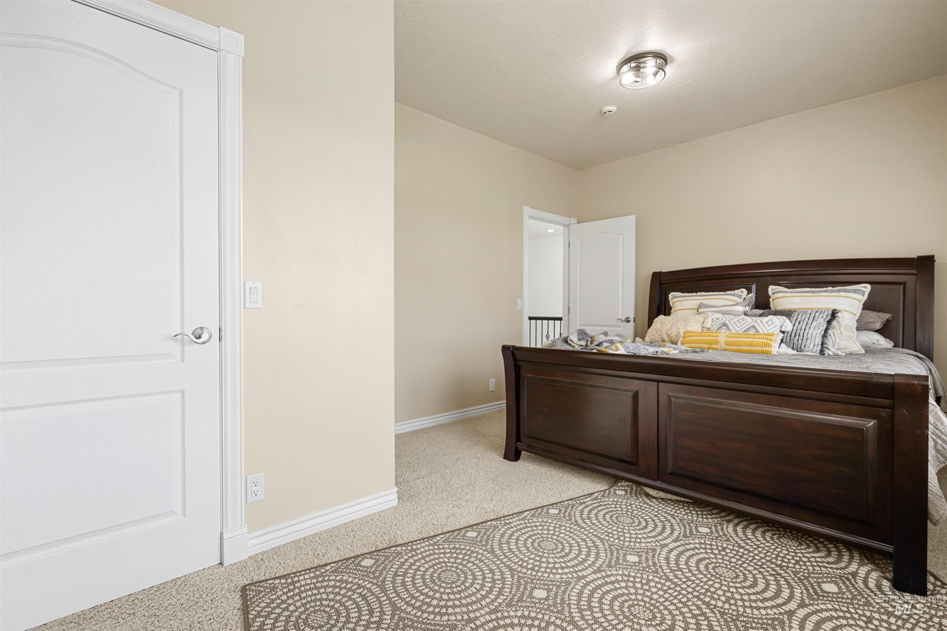 Bedroom with light colored carpet and baseboards