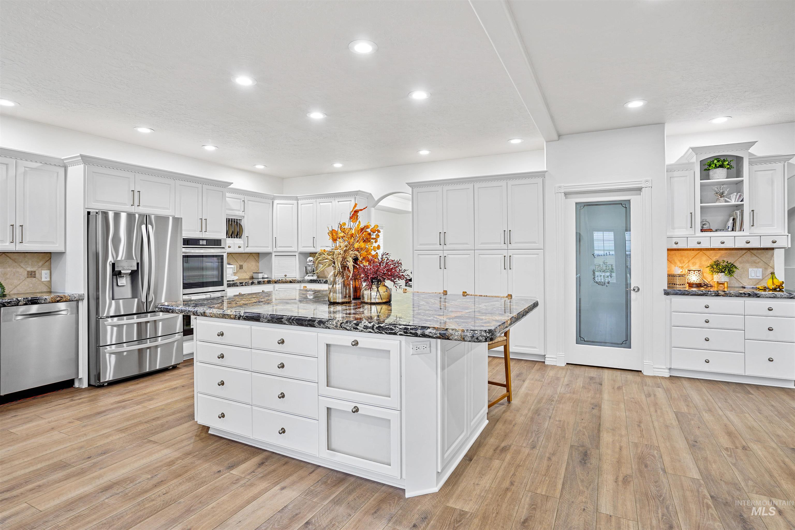 Kitchen featuring decorative backsplash, a breakfast bar, stainless steel appliances, dark stone counters, and recessed lighting
