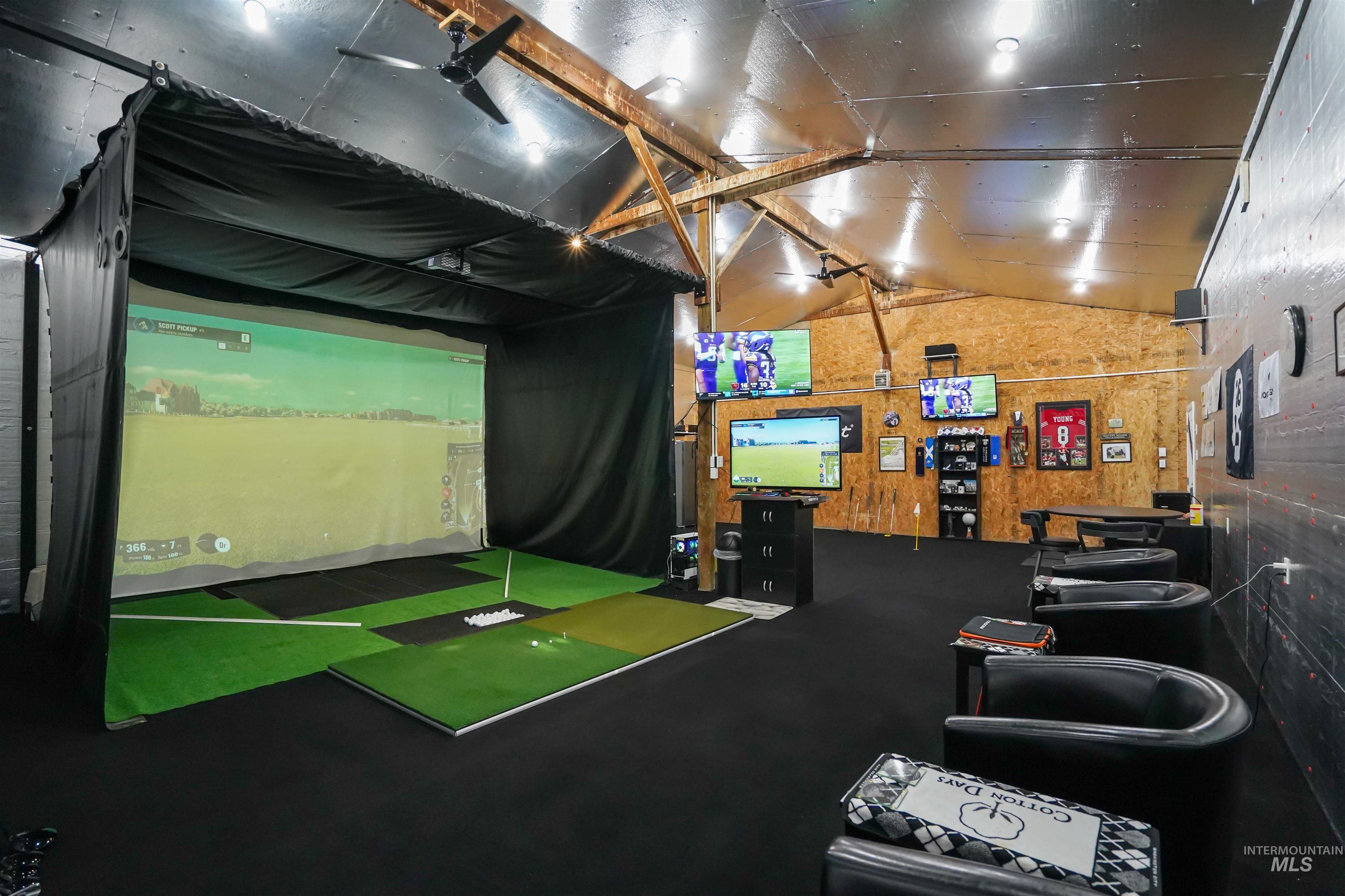 Game room featuring golf simulator, vaulted ceiling, and wood walls