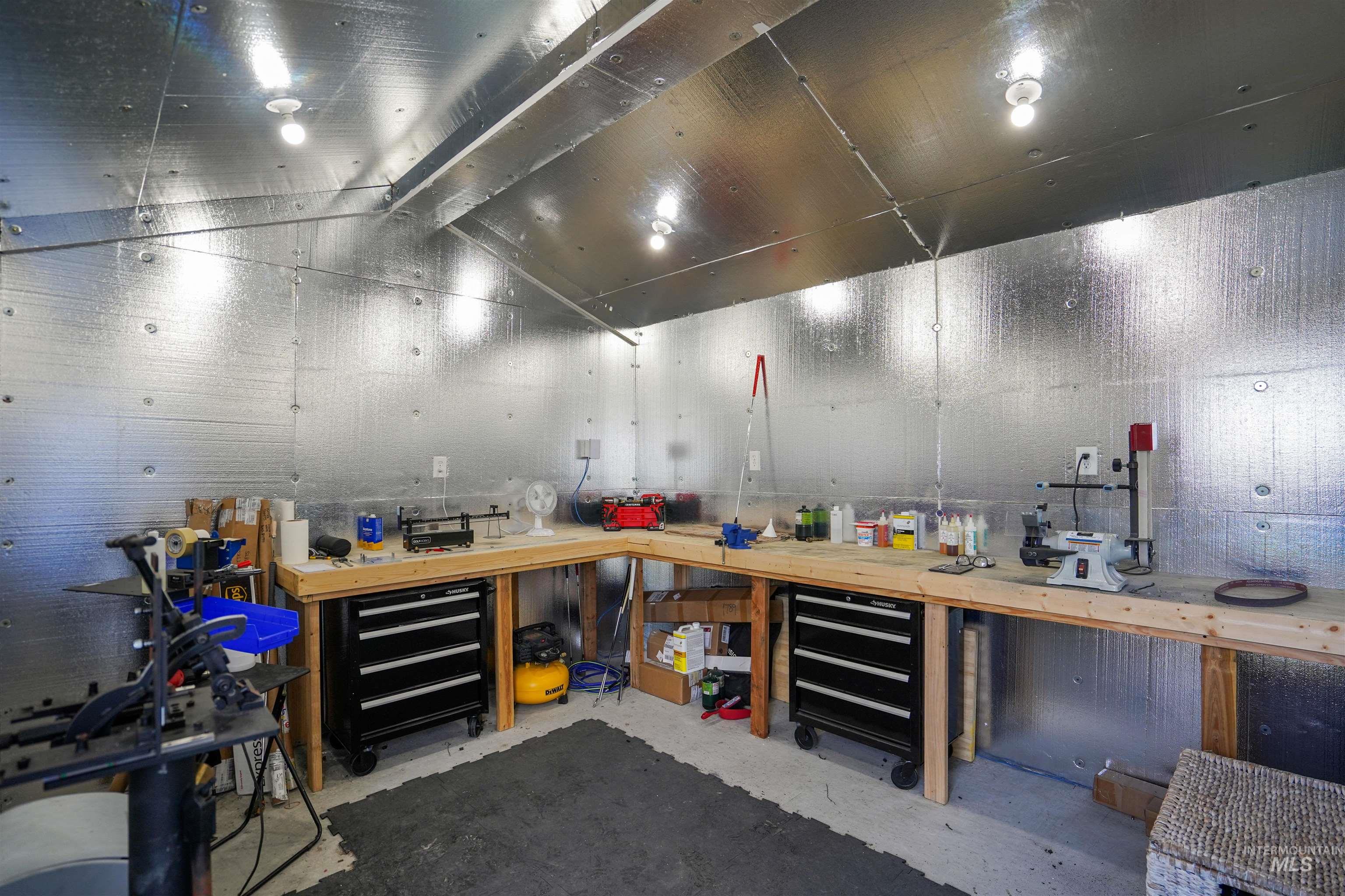 Misc room with a workshop area, unfinished concrete floors, and lofted ceiling