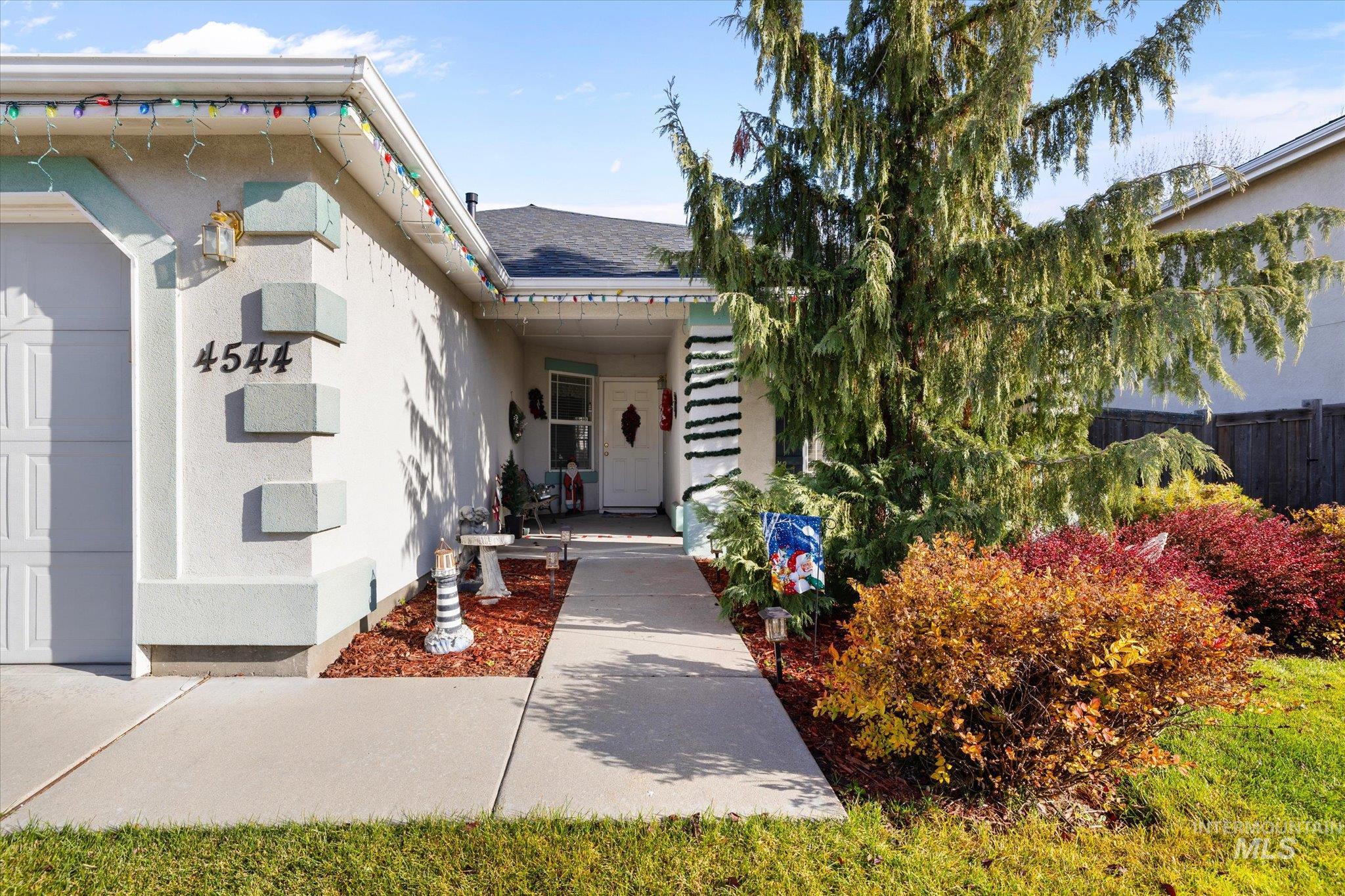 Doorway to property with stucco siding, a garage, and a shingled roof