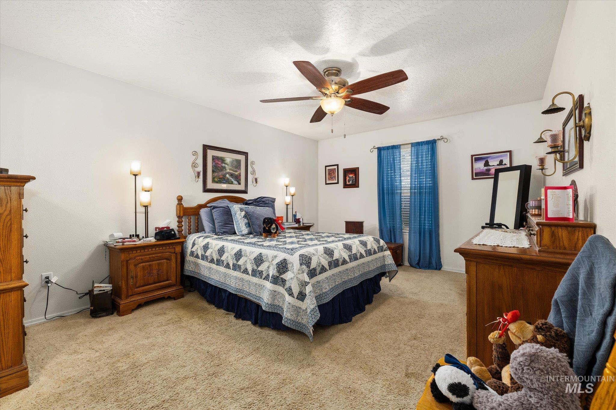 Carpeted bedroom featuring a textured ceiling and a ceiling fan