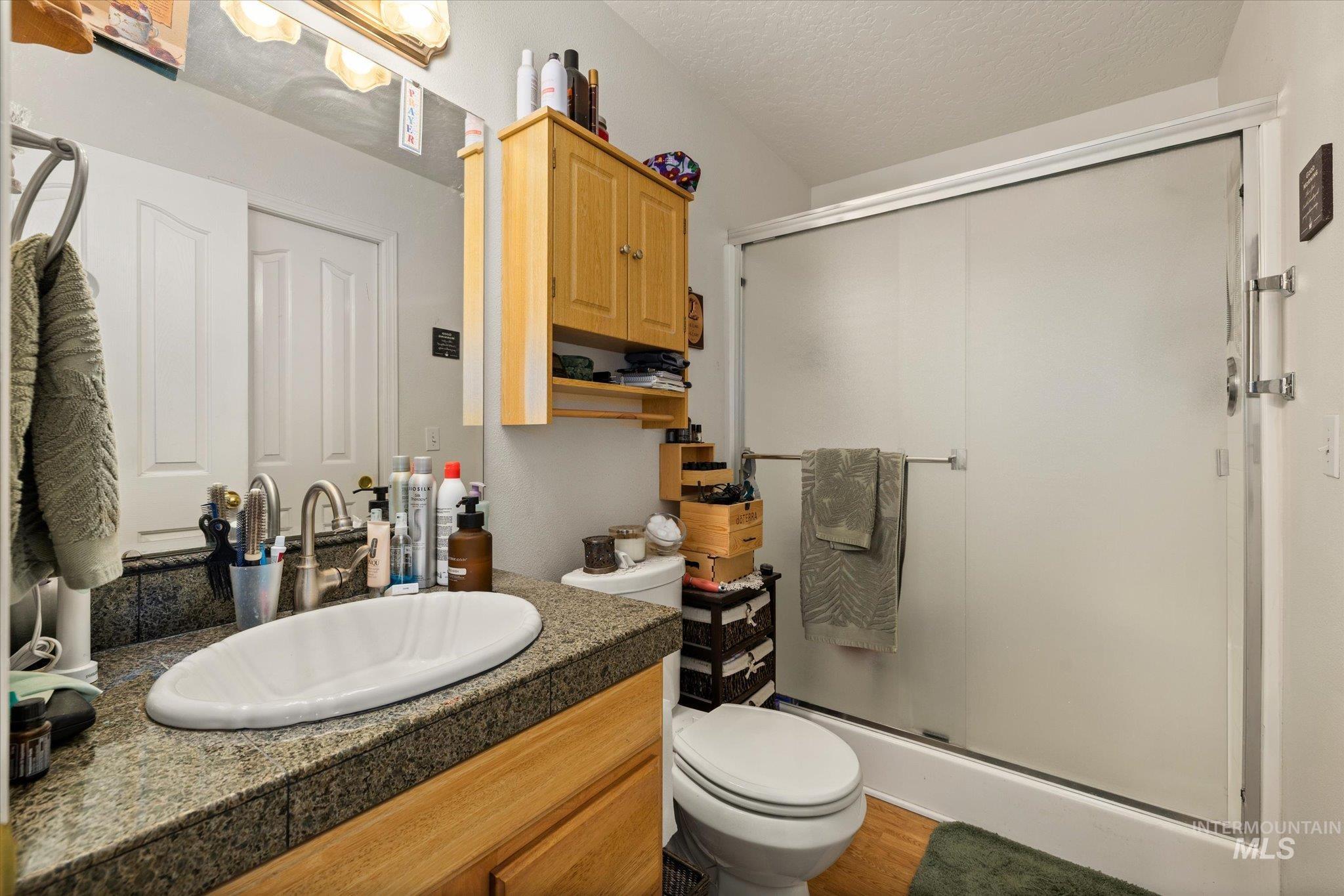 Bathroom with vanity, a shower stall, and a textured ceiling