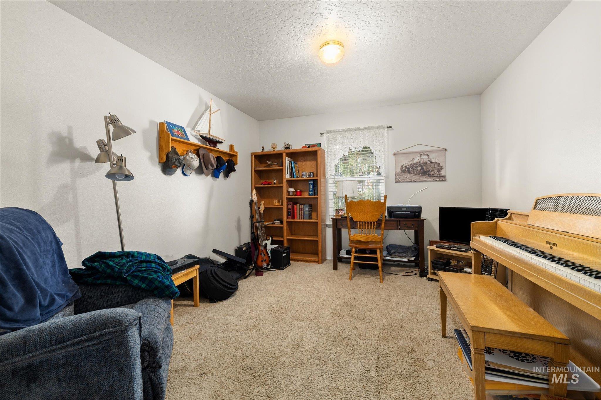 Office with a textured ceiling and light colored carpet