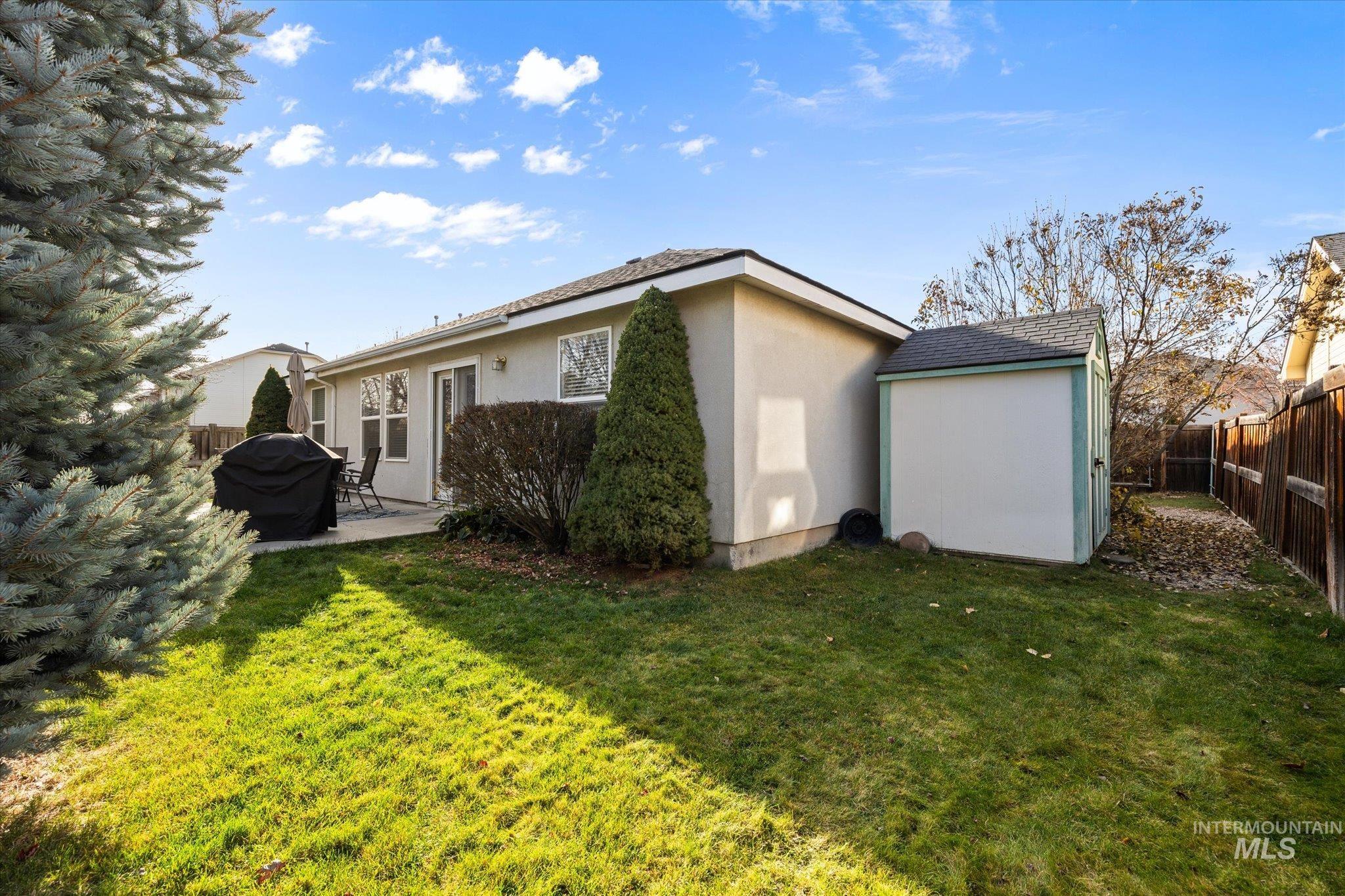 Rear view of house with a fenced backyard, a patio, stucco siding, and an outdoor structure