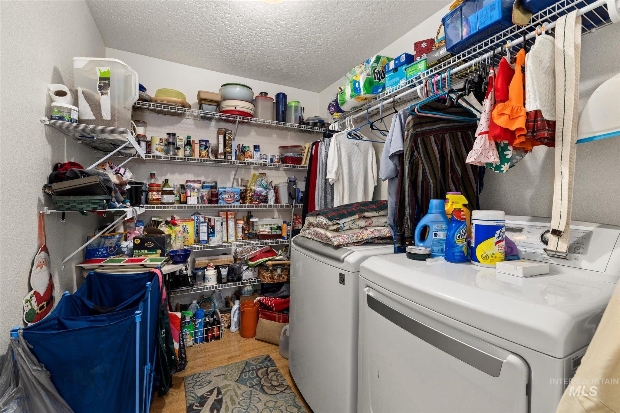 Washroom featuring separate washer and dryer, a textured ceiling, and light wood finished floors