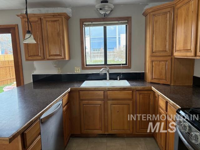 Kitchen featuring brown cabinets, dark countertops, decorative light fixtures, and healthy amount of natural light