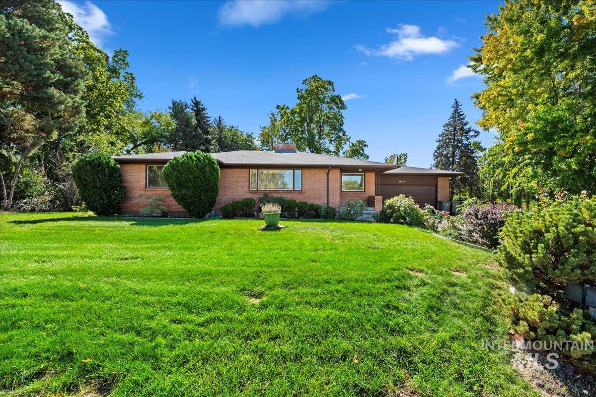 View of front of home with brick siding, a front lawn, and a garage