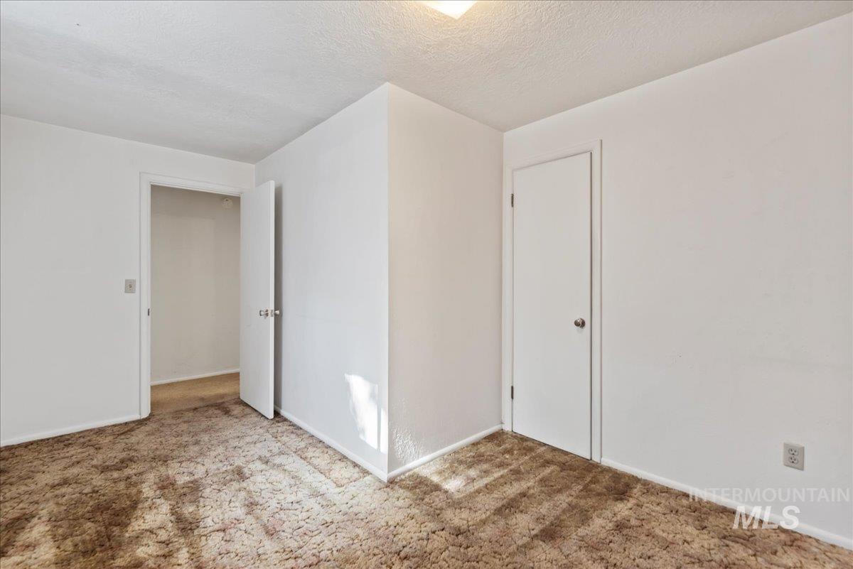 Unfurnished room (not included in bedroom count) with carpet floors and a textured ceiling