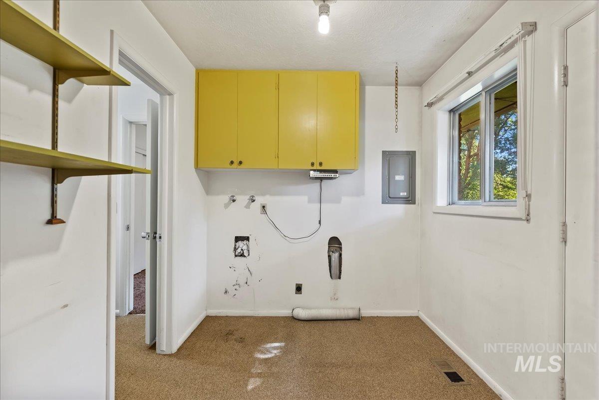 Laundry area featuring electric panel, carpet, a textured ceiling, washer hookup, and cabinet space