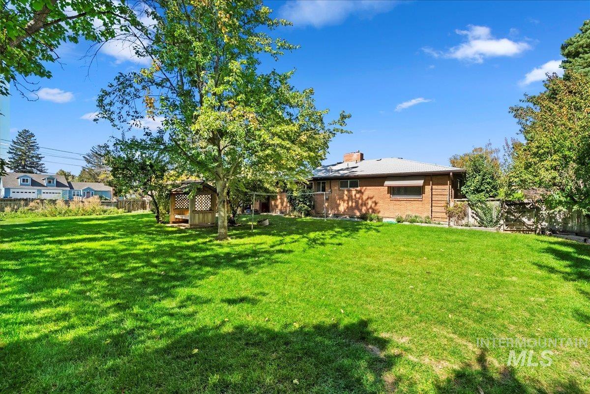 Back of property featuring a fenced backyard, a chimney, and brick siding