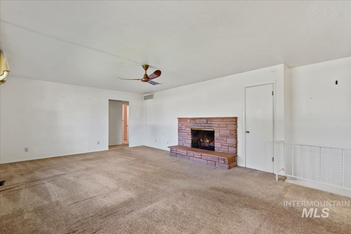 Unfurnished living room with a fireplace, carpet floors, and a ceiling fan