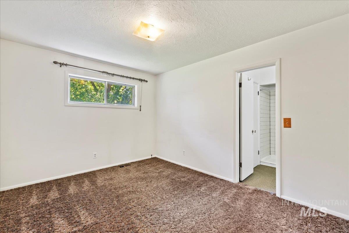 Carpeted spare room with a textured ceiling and baseboards