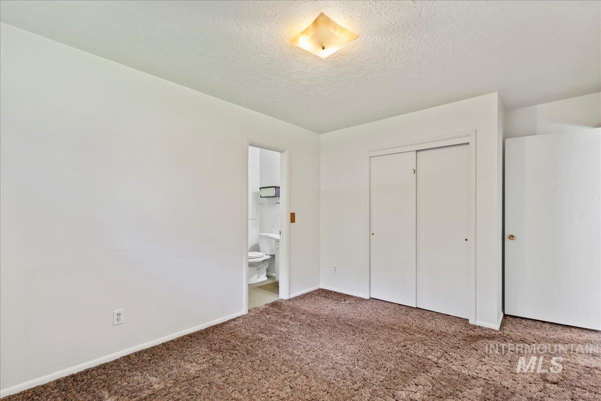 Unfurnished bedroom with a textured ceiling, carpet flooring, and a closet