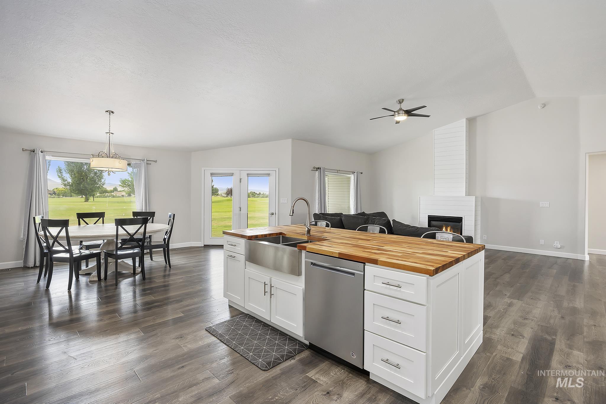 Kitchen with wood counters, white cabinets, open floor plan, vaulted ceiling, and a large fireplace