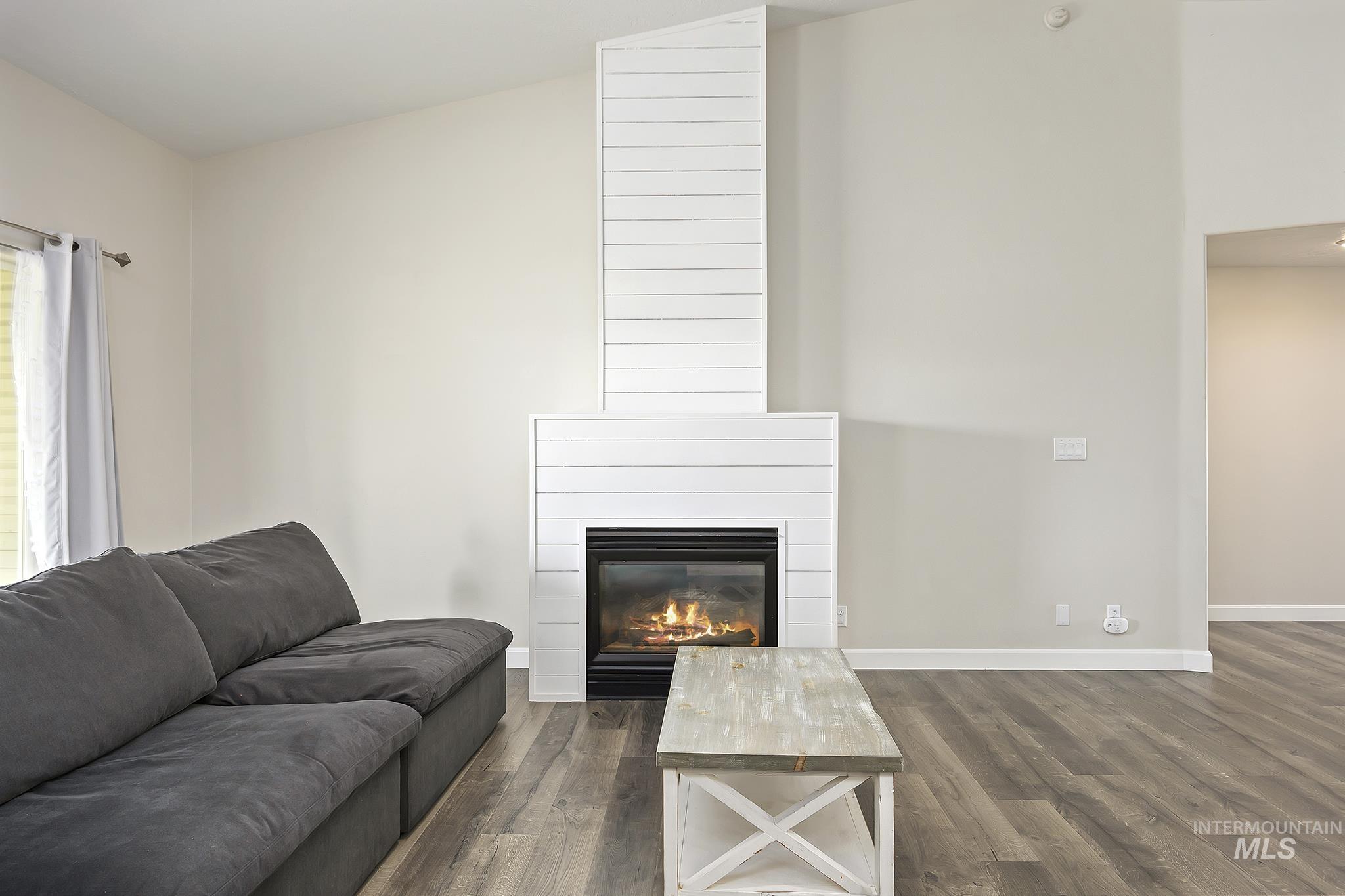 Living area with a large fireplace, dark wood-style flooring, and lofted ceiling